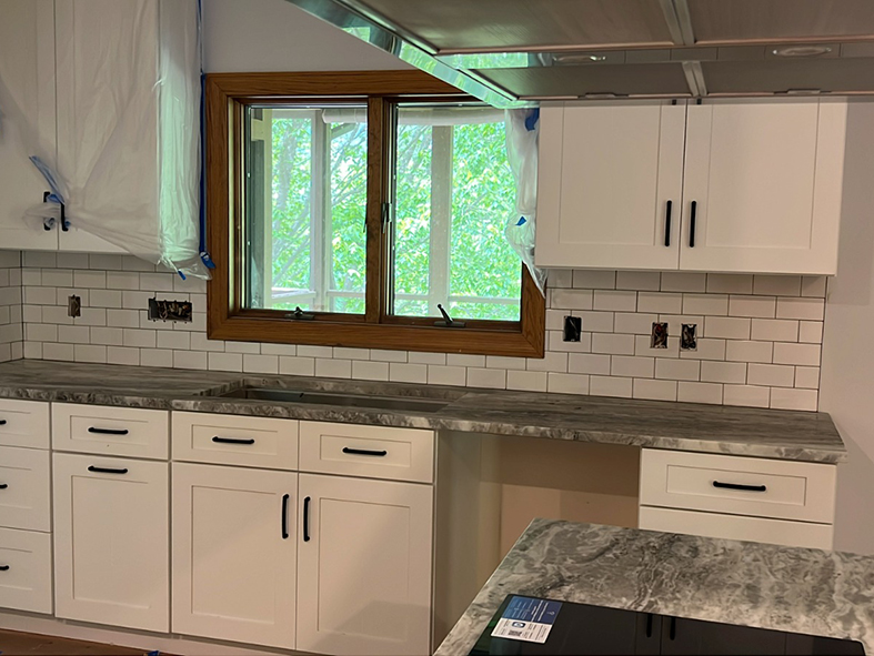 White Shaker cabinets with subway tile and marble leather finish countertop